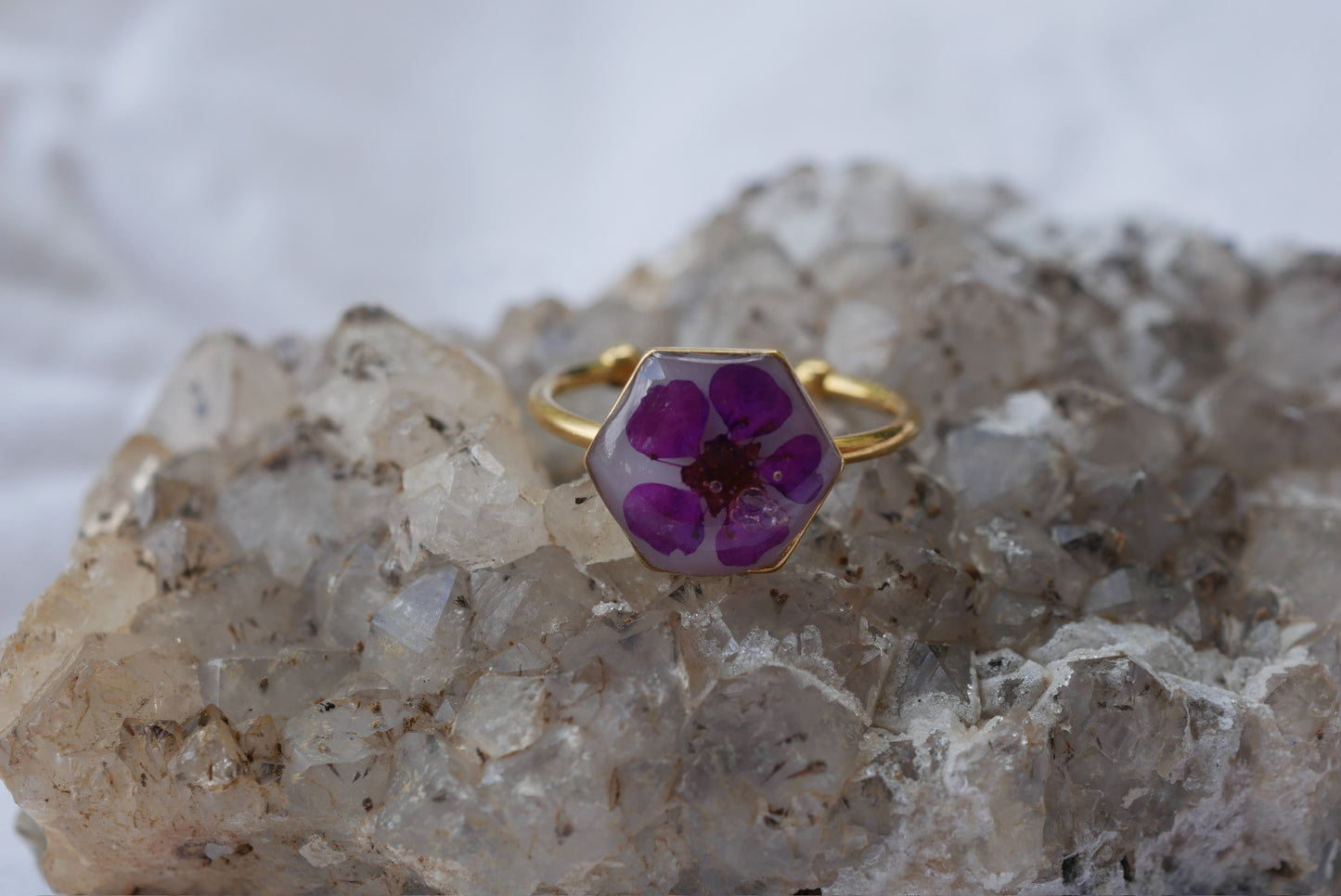 A ring with a purple flower design rests on a crystal formation.