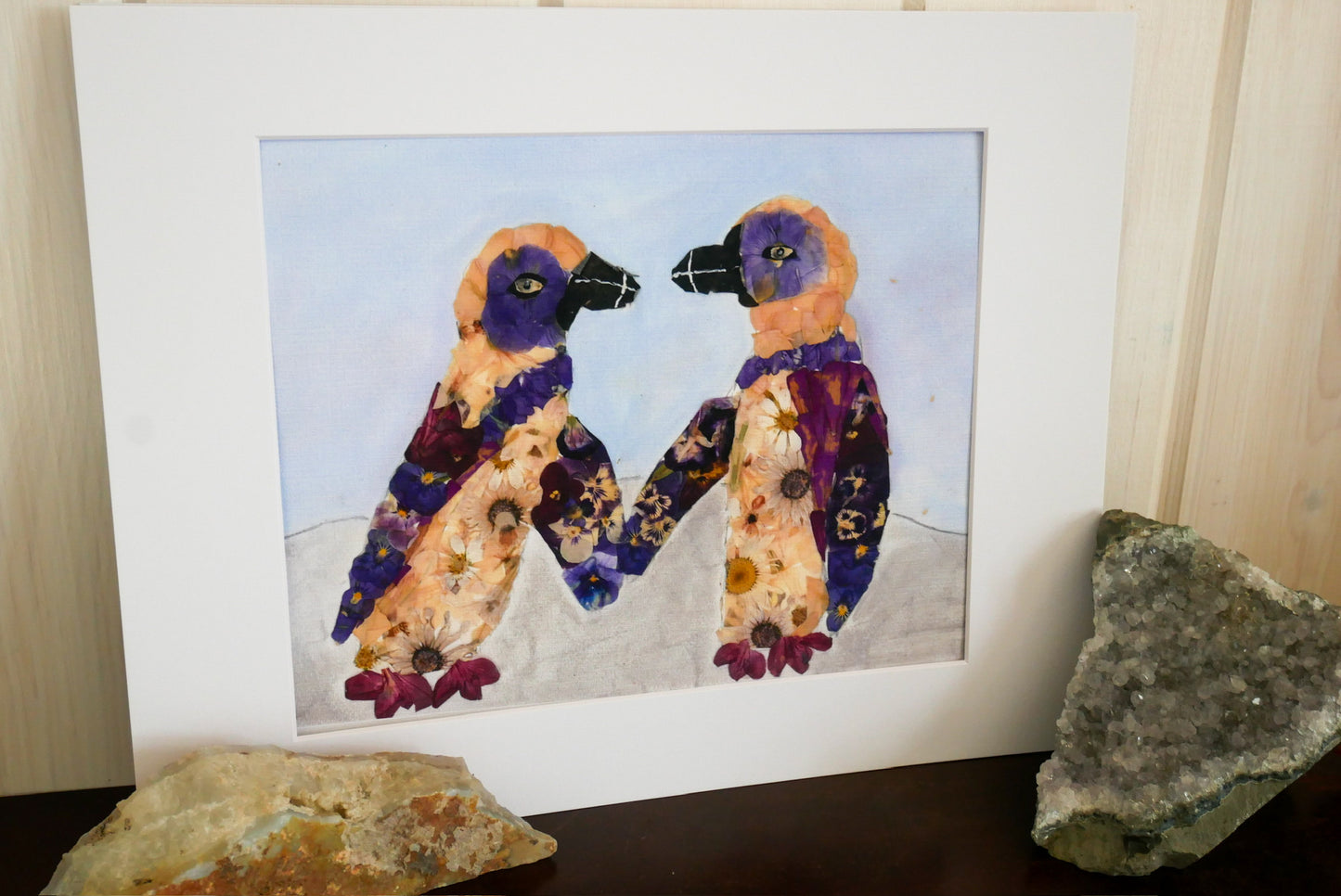 two colorful birds, possibly penguins, standing next to each other and holding hands, with a background of blue sky and clouds.