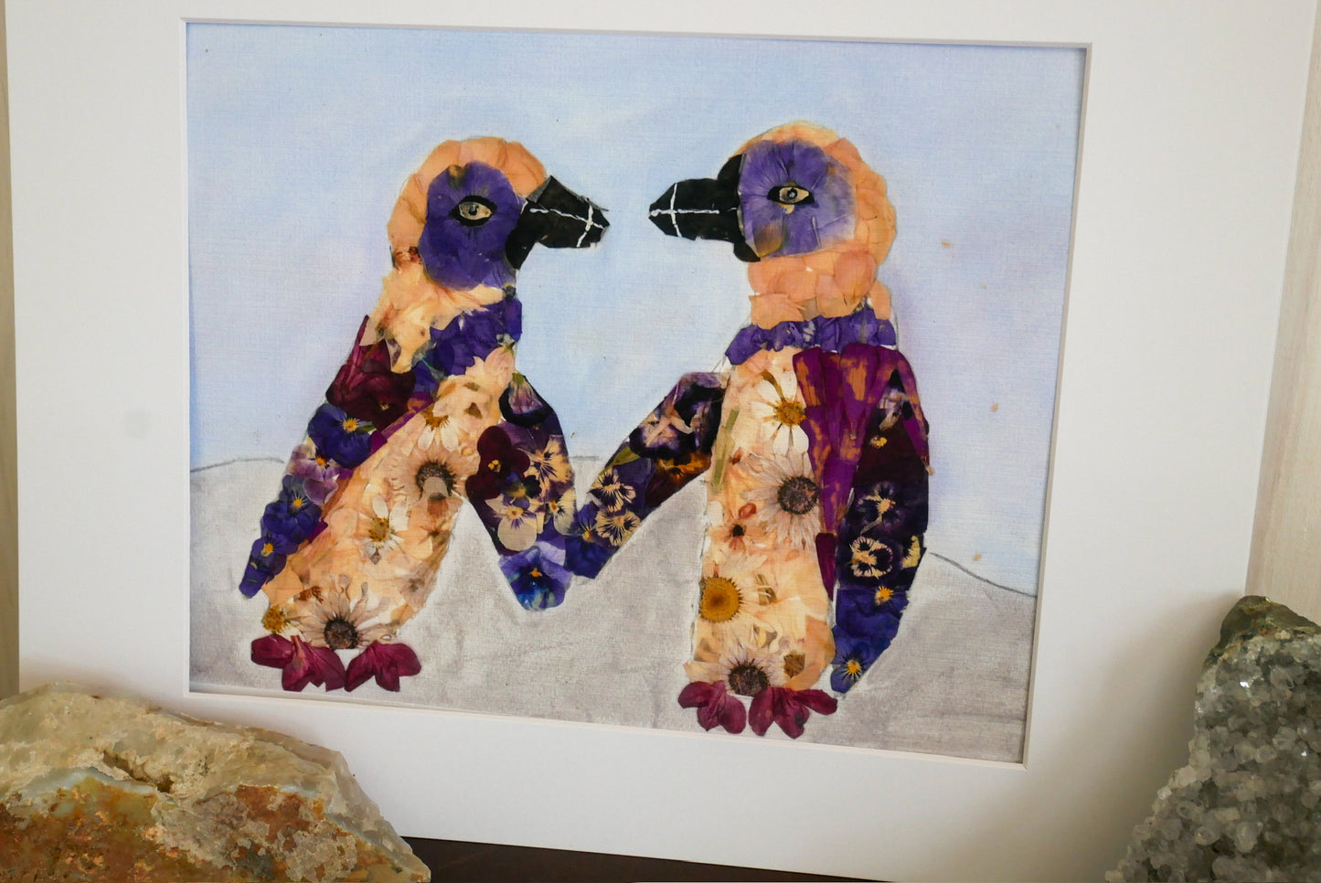 The image is a collage of two colorful birds, each with a flower-like design on their bodies, set against a blue background.