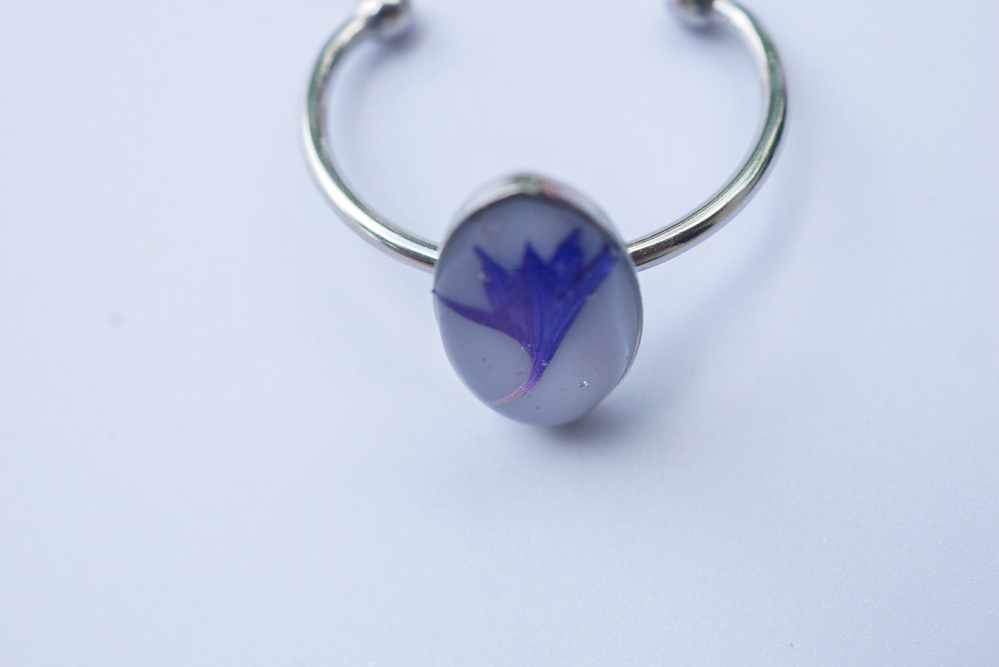 A silver ring with a blue flower design on it.