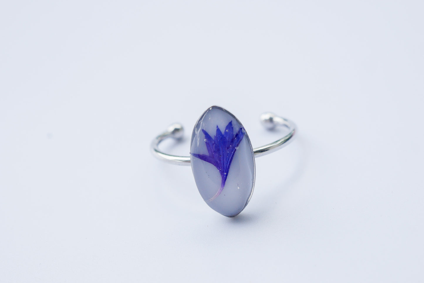 A silver ring with a blue flower design on it.
