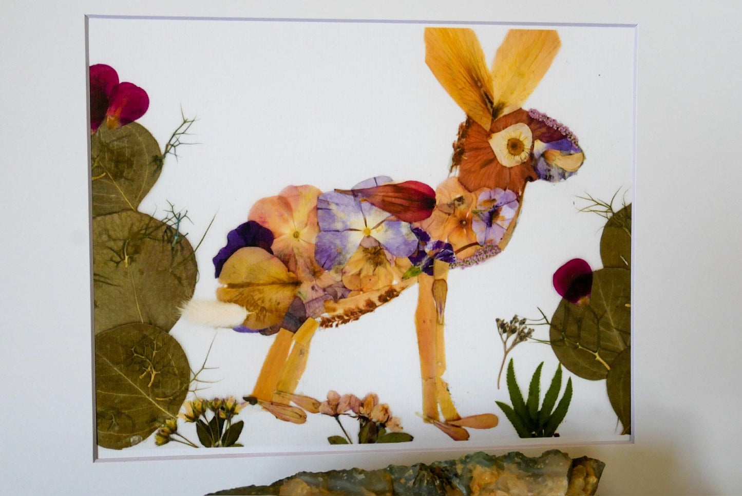 The image is a collage of various natural elements, including a cactus, flowers, and leaves, arranged to create the shape of a rabbit.