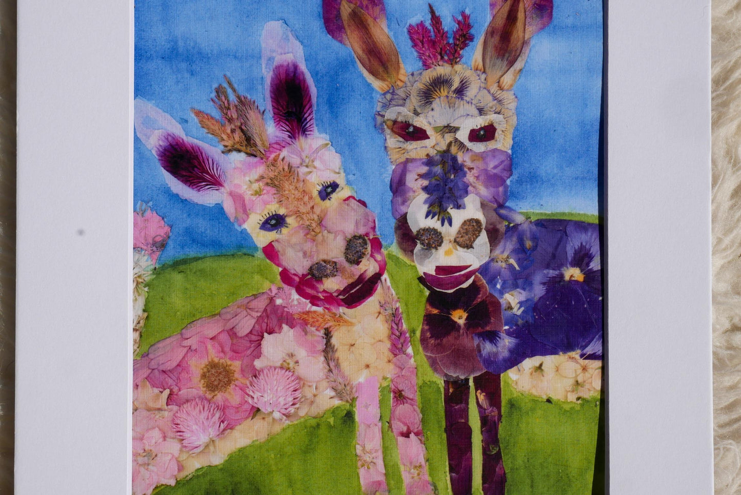 A collage of two vibrant, flower-covered animals, one pink and one purple, set against a blue background.
