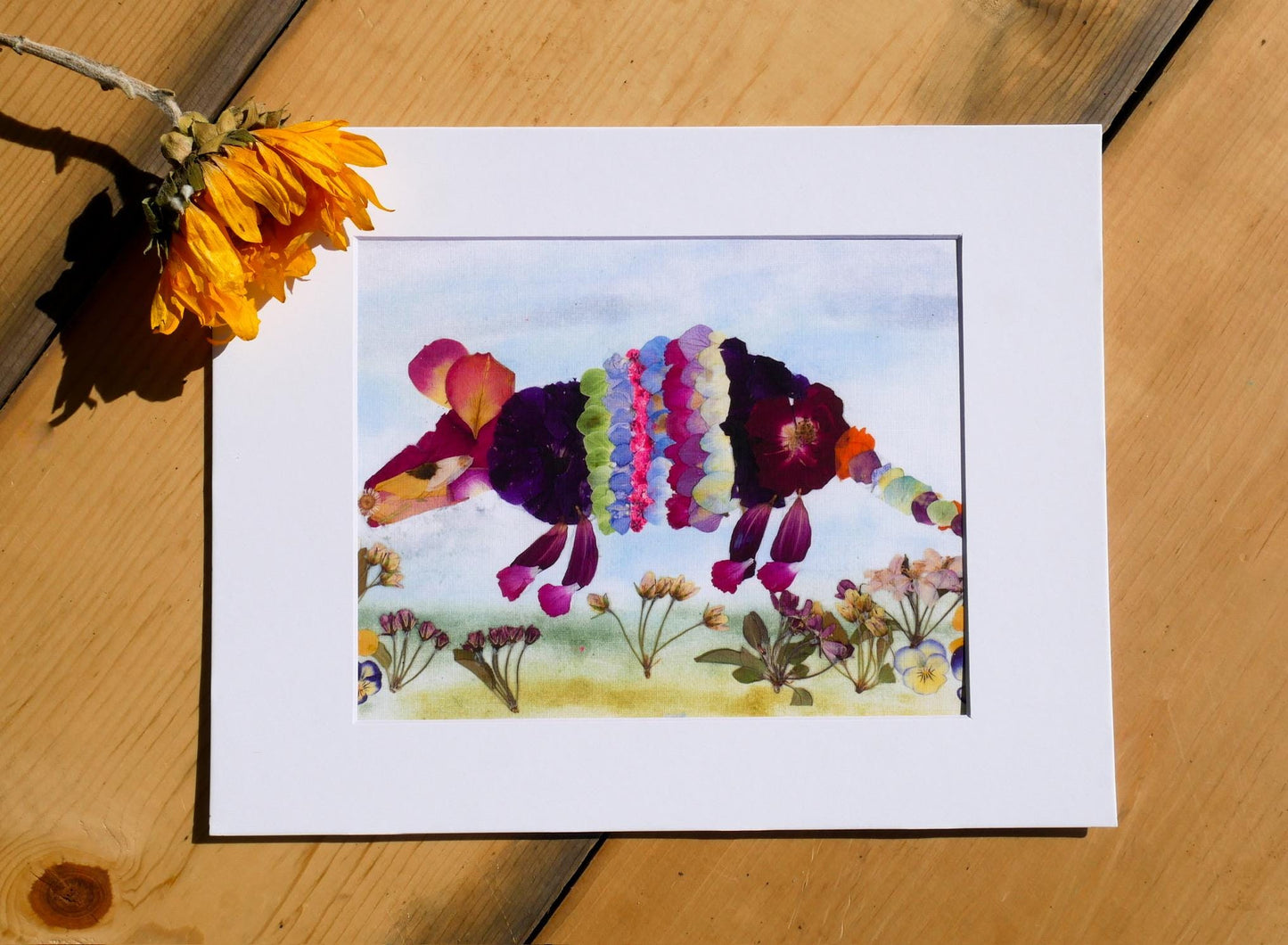 A framed artwork depicting a colorful, abstract representation of a flower or plant, with vibrant petals and leaves in various colors.