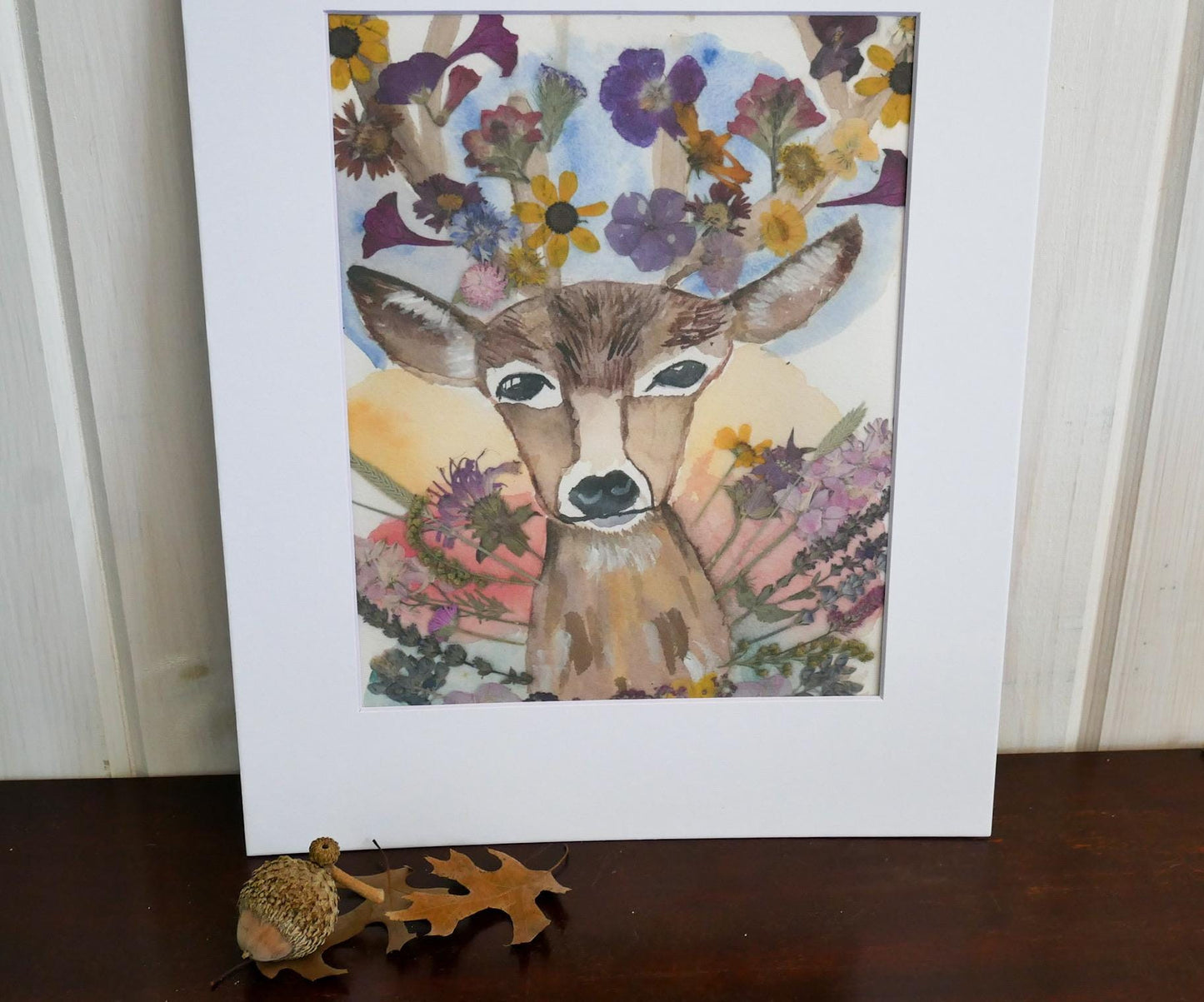 a deer with antlers, surrounded by a colorful array of flowers and leaves, creating a vibrant and lively scene.