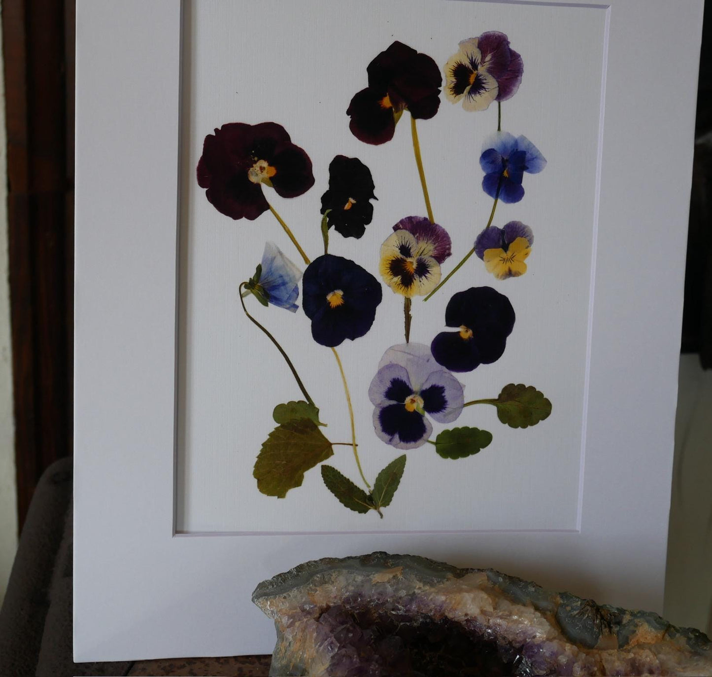 a framed print of a flower arrangement with various colored flowers, including purple, blue, and yellow ones, displayed on a white background.