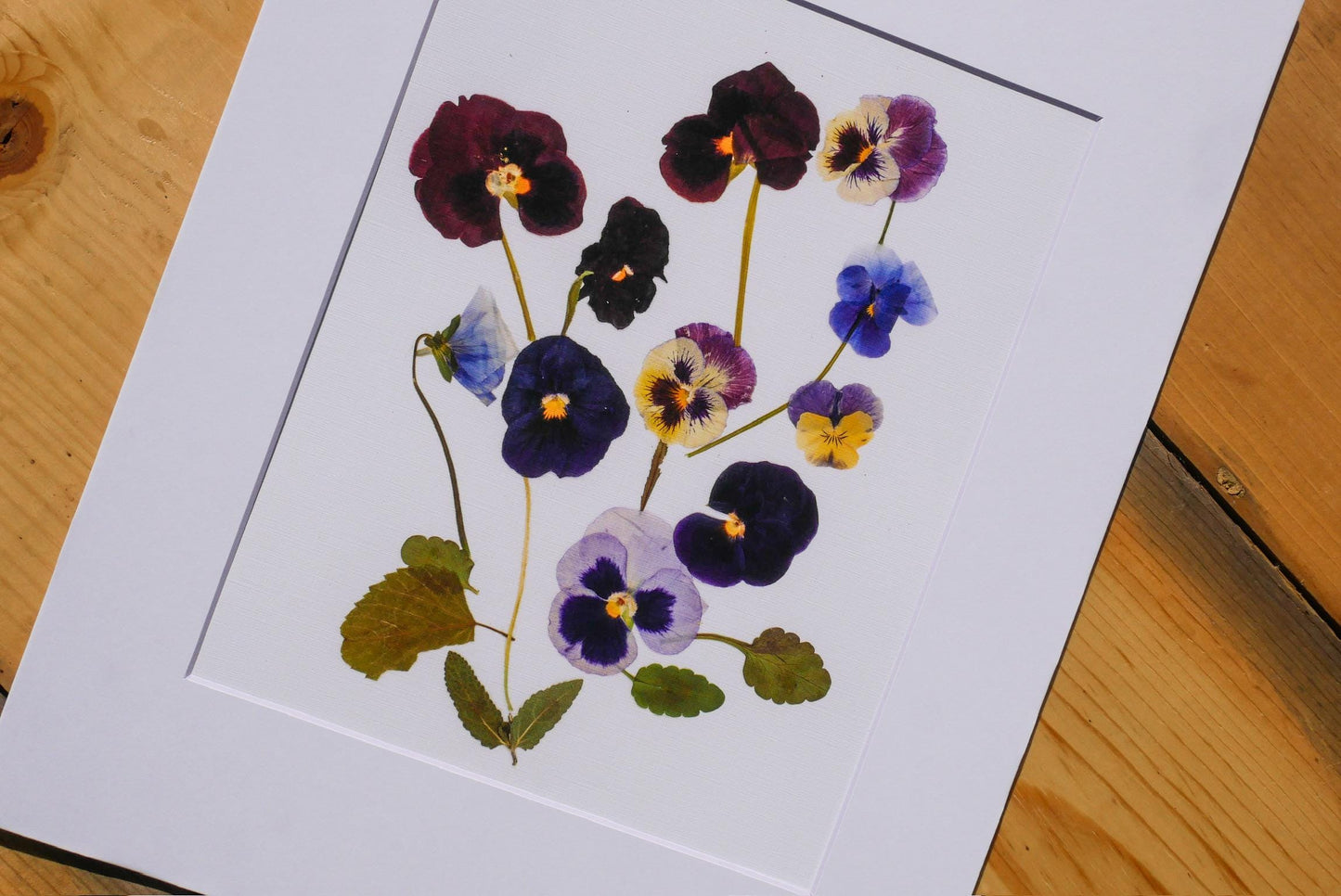 a close-up view of a framed print with a vibrant arrangement of colorful flowers, including purple, blue, and yellow blooms.