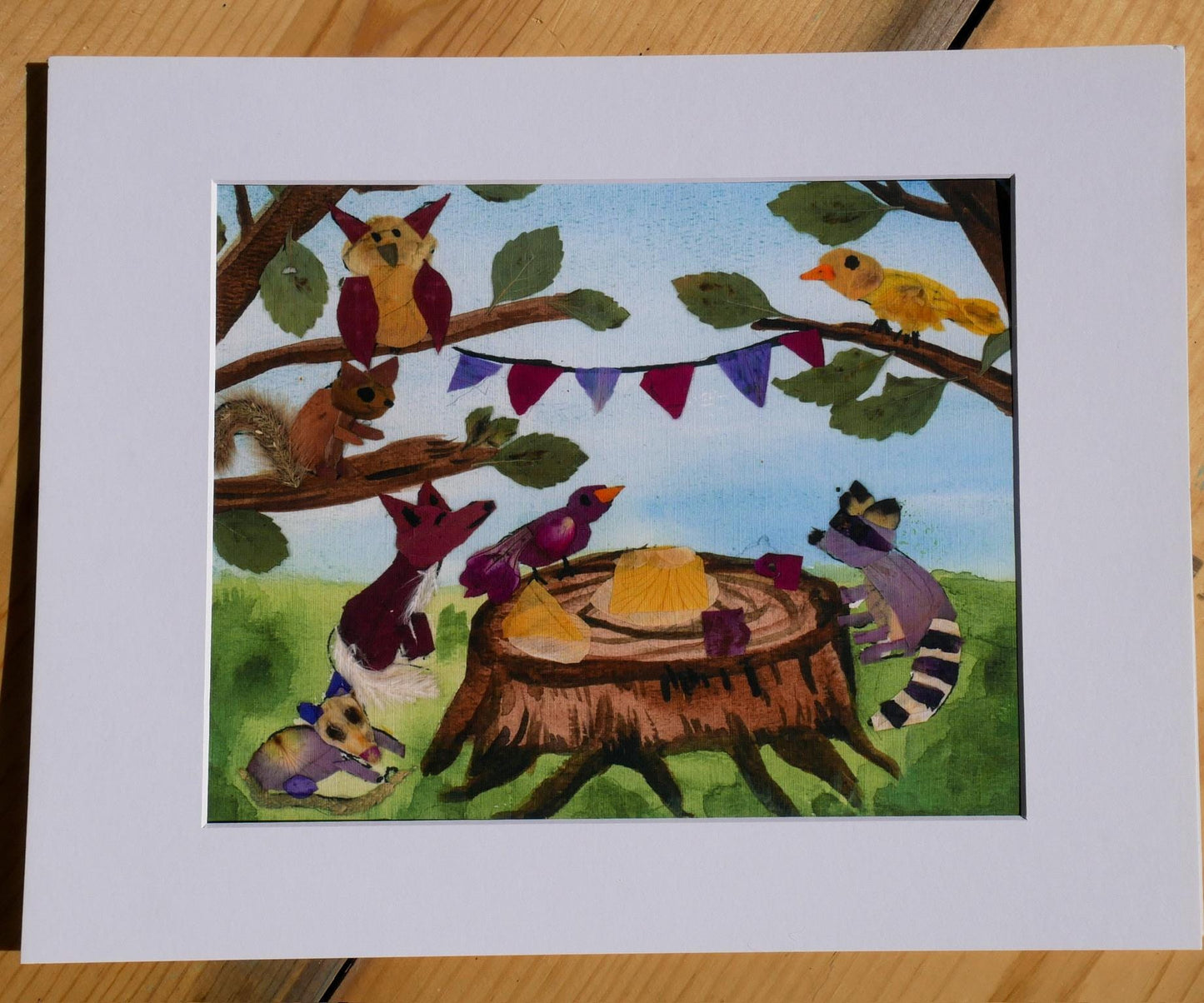 A collage of various animals, including a bird, squirrel, raccoon, and fox, gathered around a tree stump with a plate of food on it, set against a backdrop of a blue sky and green foliage.