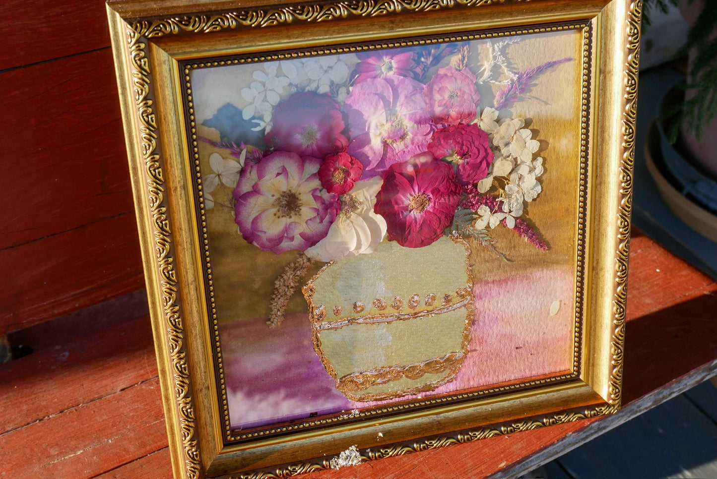 A framed painting depicting a vase filled with a variety of colorful flowers, including pink and white roses, white and purple flowers, and other blooms.
