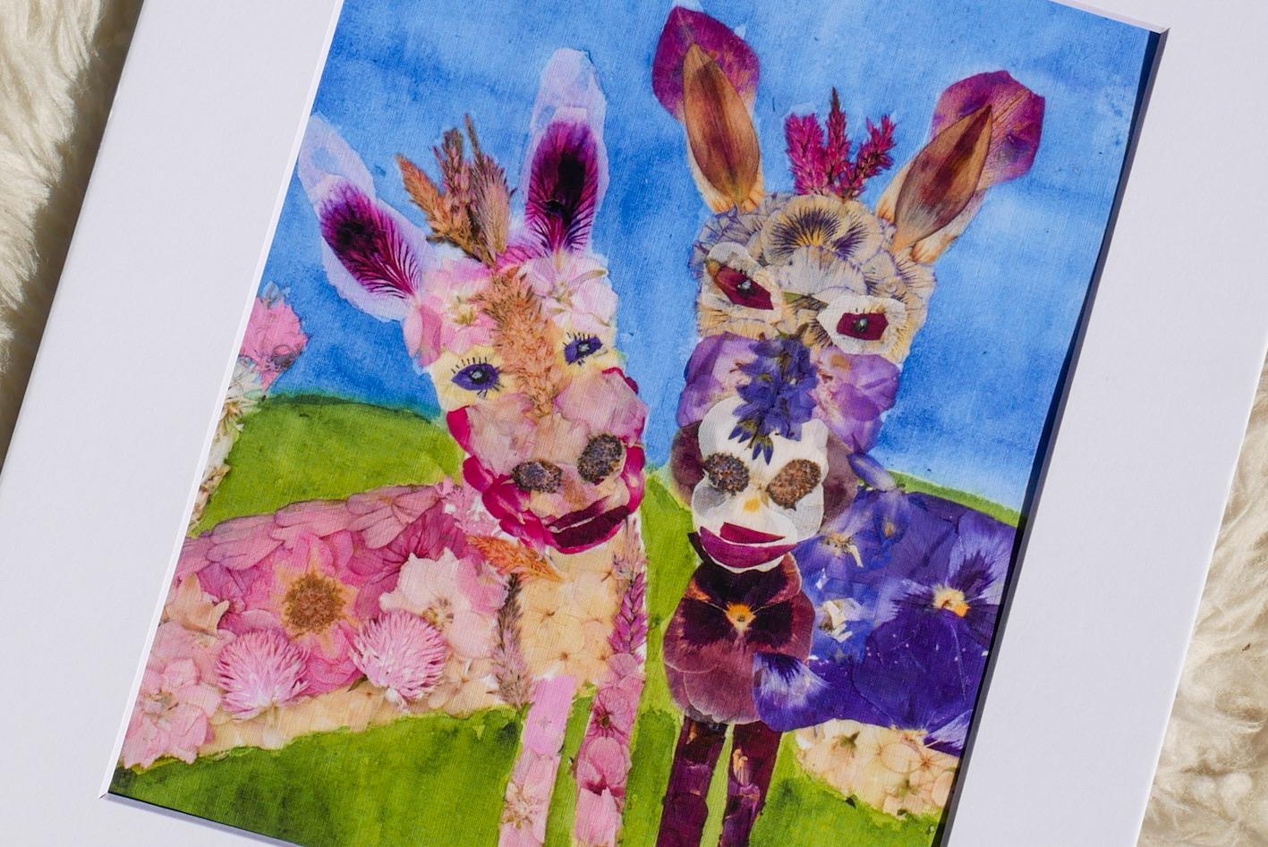 A collage of two vibrant, flower-adorned animal faces, one pink and one purple, set against a blue background.