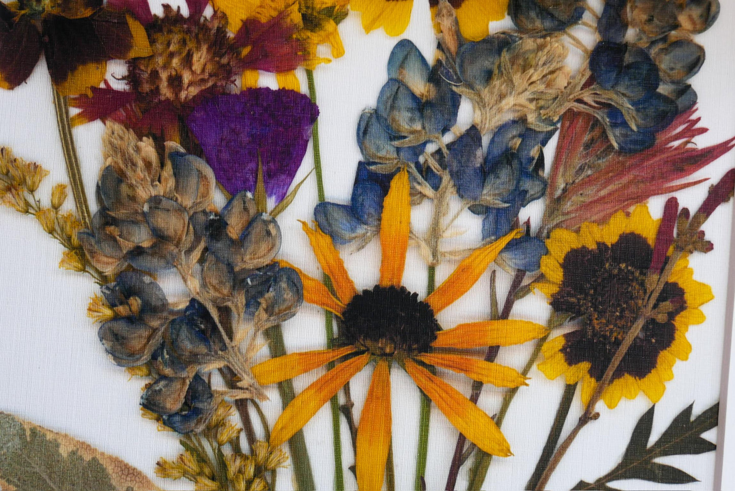 The image is a close-up of a variety of colorful dried flowers, including sunflowers, daisies, and other blooms, arranged in a visually appealing manner.