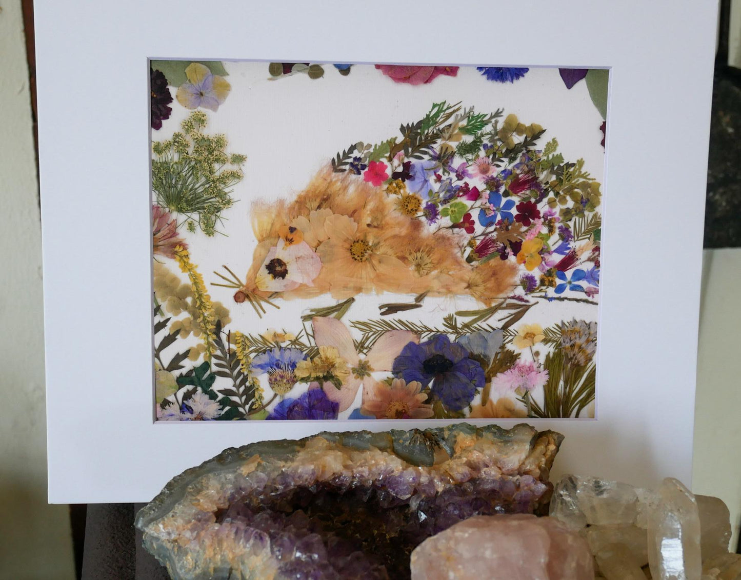 a vibrant and colorful arrangement of flowers and plants, with a hedgehog-like creature made of dried flowers as the central focus.