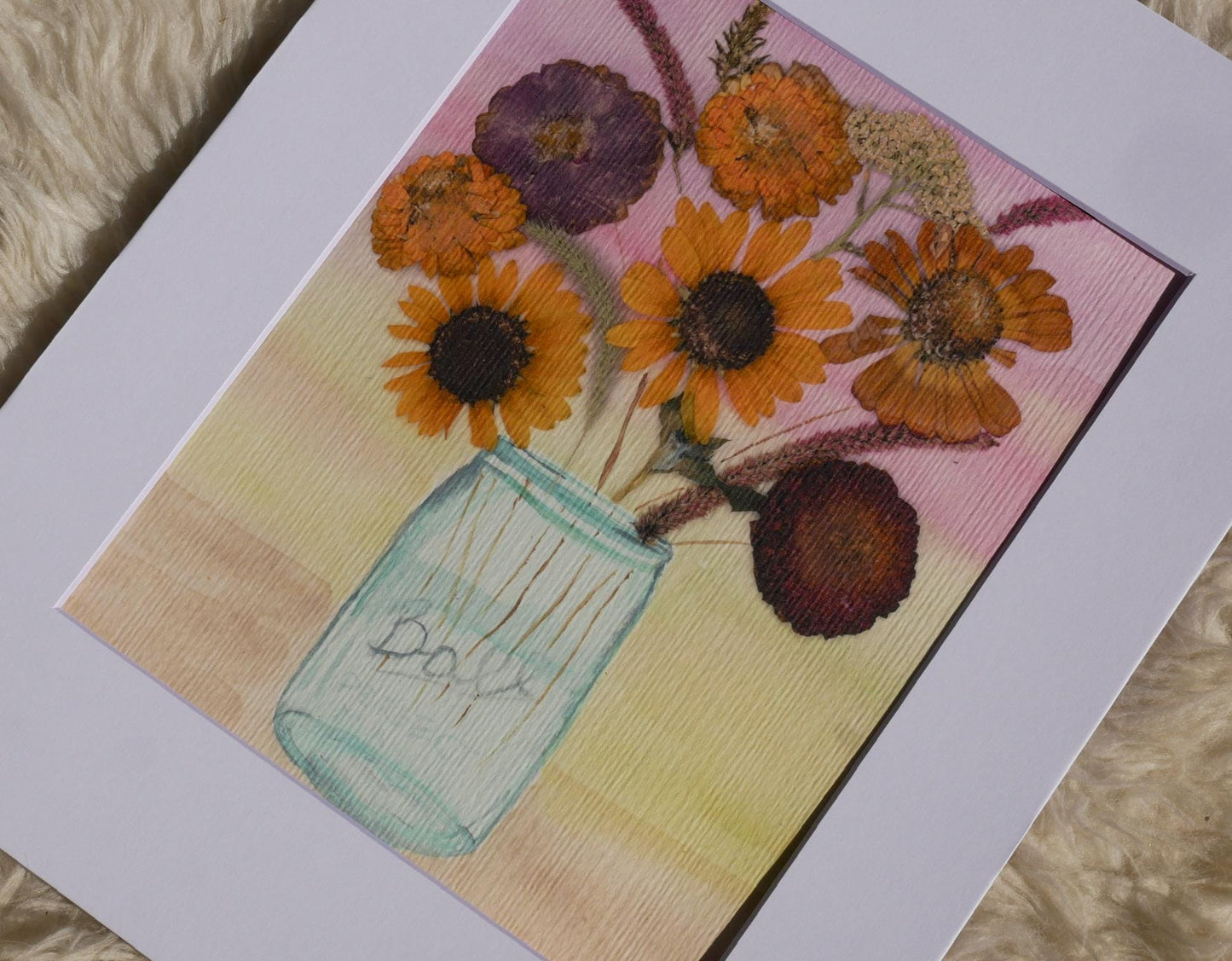 A framed painting depicting a vase filled with a variety of colorful flowers, including sunflowers and other blooms, set against a pink and yellow background.