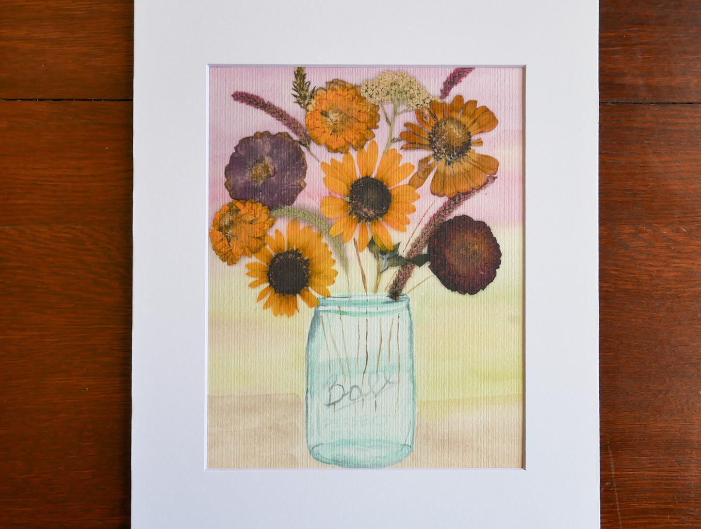 A framed painting depicting a vase filled with a variety of colorful flowers, including sunflowers and other blooms, set against a pink and yellow background.