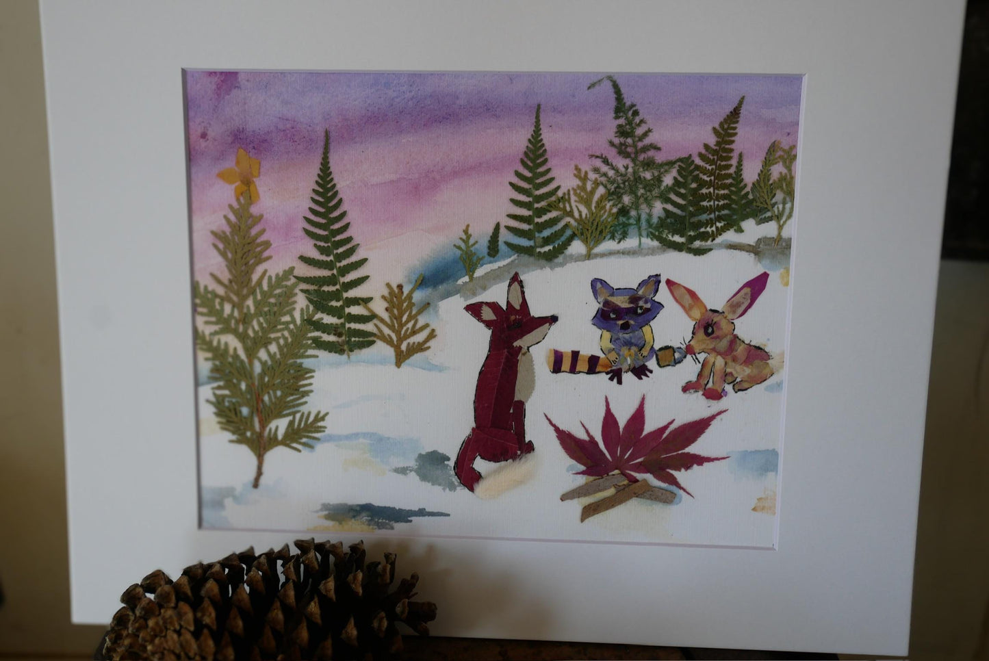 A watercolor painting depicting a snowy forest scene with three cartoon animals - a fox, a raccoon, and a rabbit - sitting on the snow.