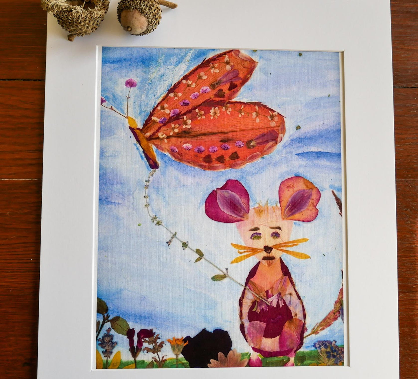 The image is a collage featuring a butterfly and a mouse, both crafted from flowers and leaves, set against a blue sky background.