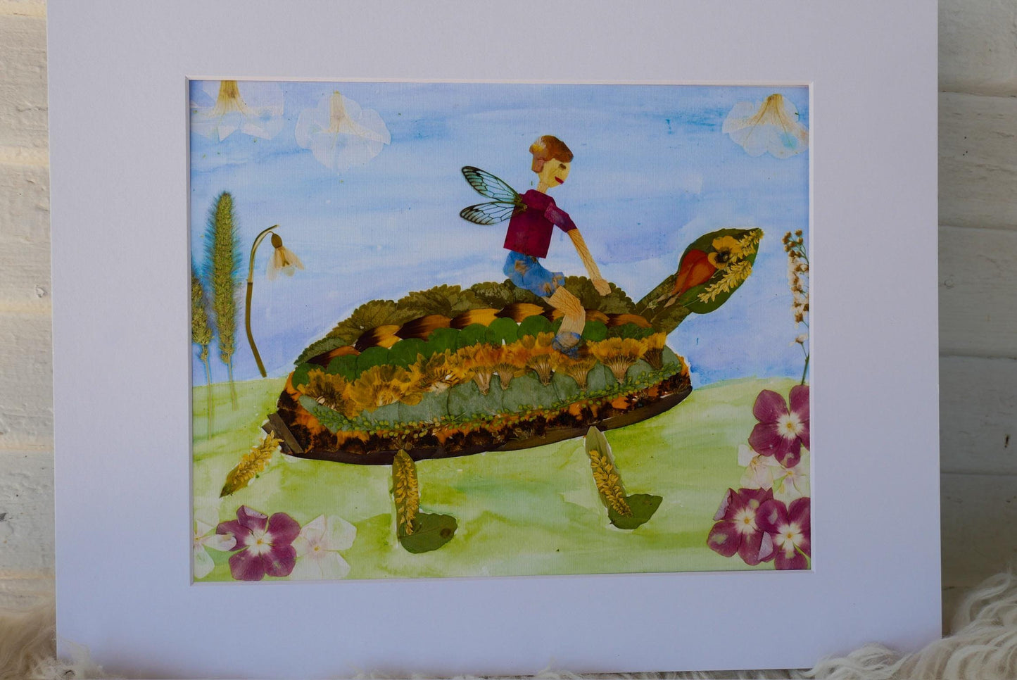 A painting depicting a young boy riding a large, colorful turtle through a field with flowers.