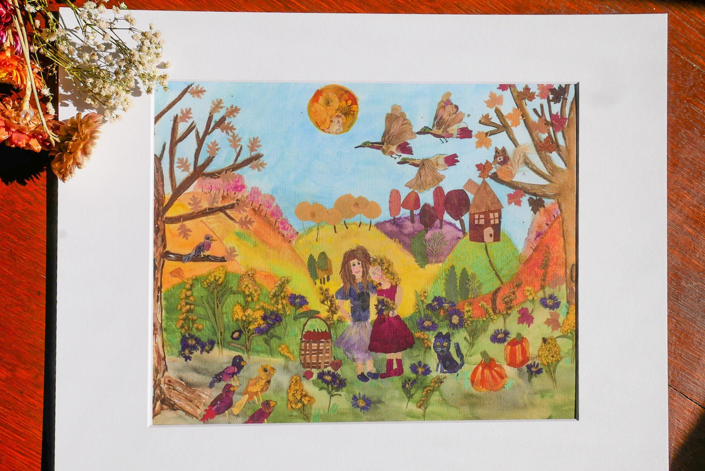 The image is a colorful painting depicting a lively autumn scene with a woman, a cat, and various birds in a field surrounded by trees and houses.